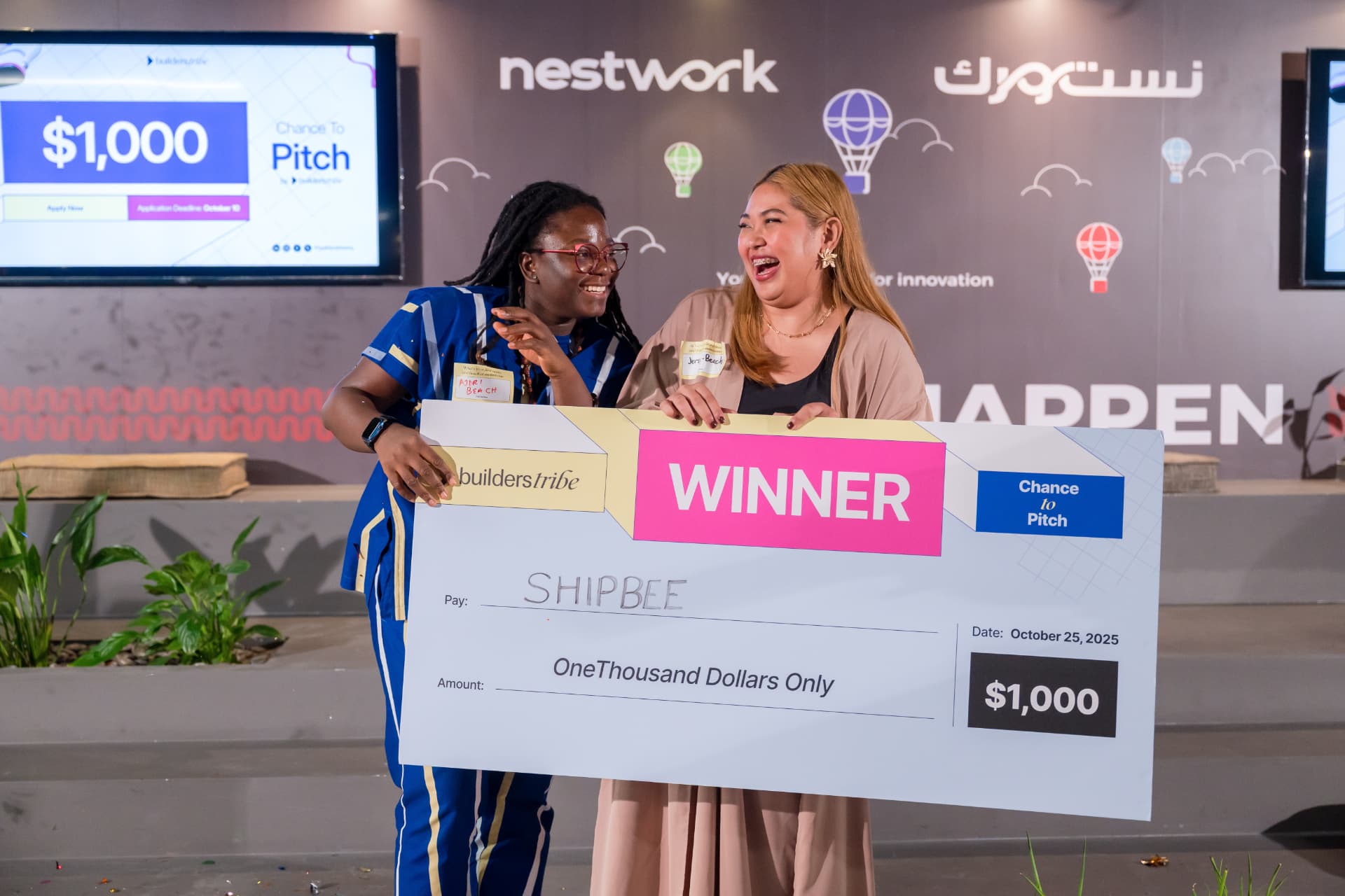 Two startup pitch winners holding a celebratory cheque onstage