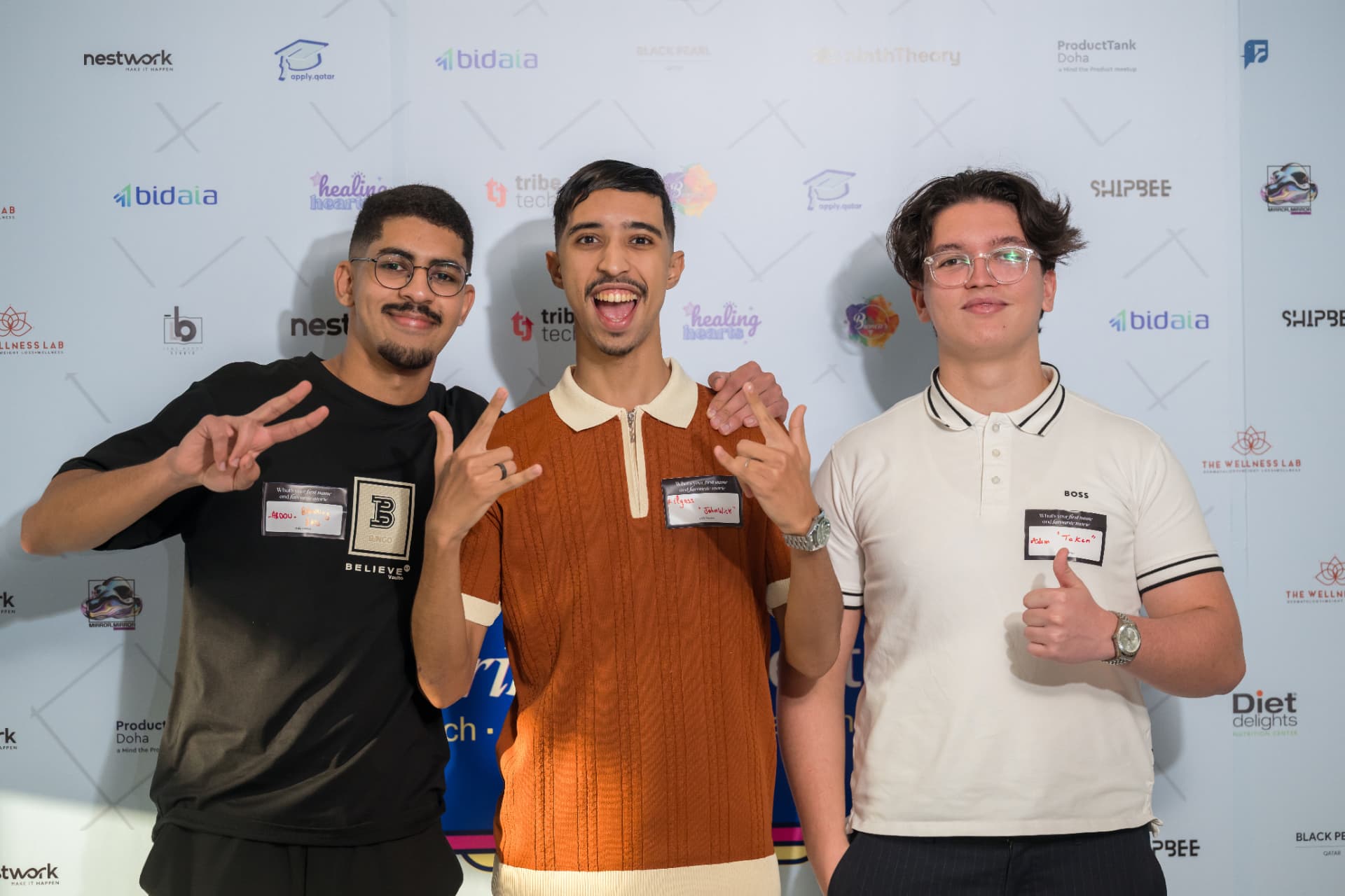 Three attendees posing together in front of sponsor logos